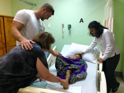 Tim Tebow praying with a patient at the Tebow CURE Hospital.jpg